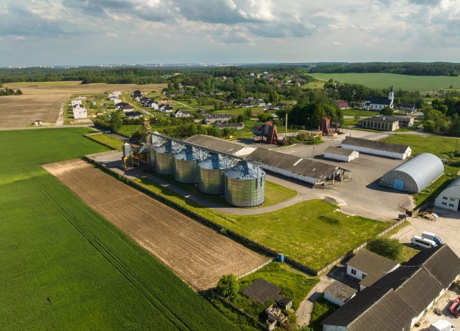 Uma vista aérea de uma fazenda com silos no meio de um campo.